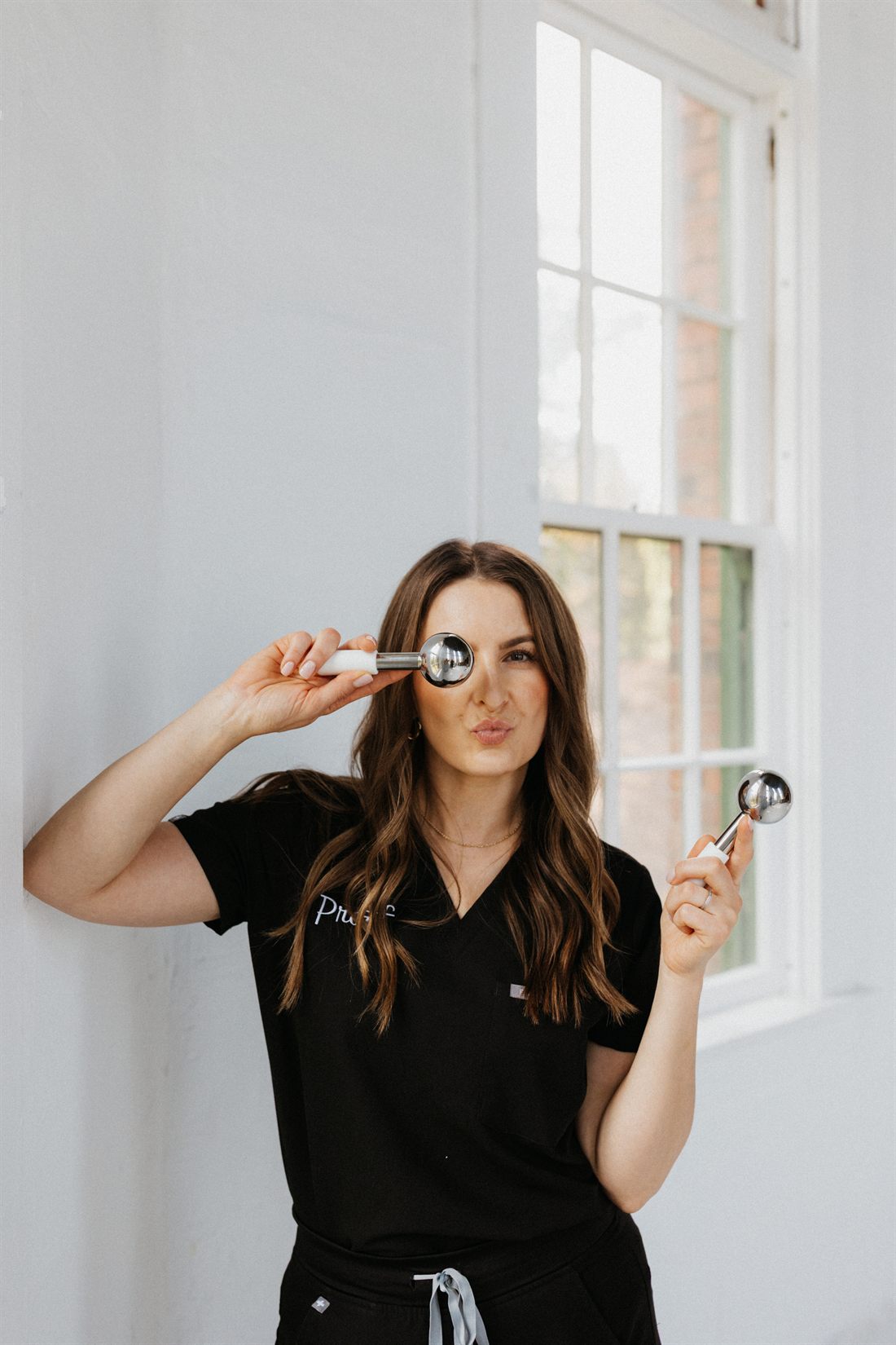 Diana Limonov, Master Aesthetician, holding chrome ice globes used in facial treatments.